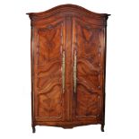 A Louis XV walnut armoire , circa 1750, the the arched pediment above a pair...  A Louis XV walnut