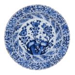 A Chinese blue and white dish, Kangxi, painted with flowers issuing from...  A Chinese blue and