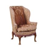 An upholstered wing armchair in George II style , 20th century  An upholstered wing armchair in