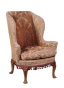 An upholstered wing armchair in George II style , 20th century  An upholstered wing armchair in