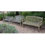 A pair of teak garden benches, with arched and slatted back and seat A pair of teak garden