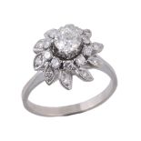 A diamond cluster ring, the central brilliant cut diamond in a raised claw...  A diamond cluster