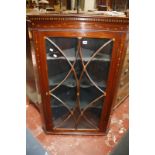 A late Georgian mahogany hanging corner cabinet with an astragal glazed door and satinwood inlay.