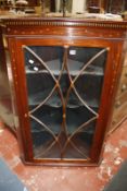 A late Georgian mahogany hanging corner cabinet with an astragal glazed door and satinwood inlay.