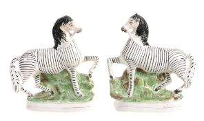 A pair of Staffordshire pottery models of zebras, mid 19th century  A pair of Staffordshire