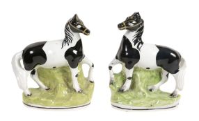 A pair of Staffordshire pottery models of piebald horses, mid 19th century  A pair of