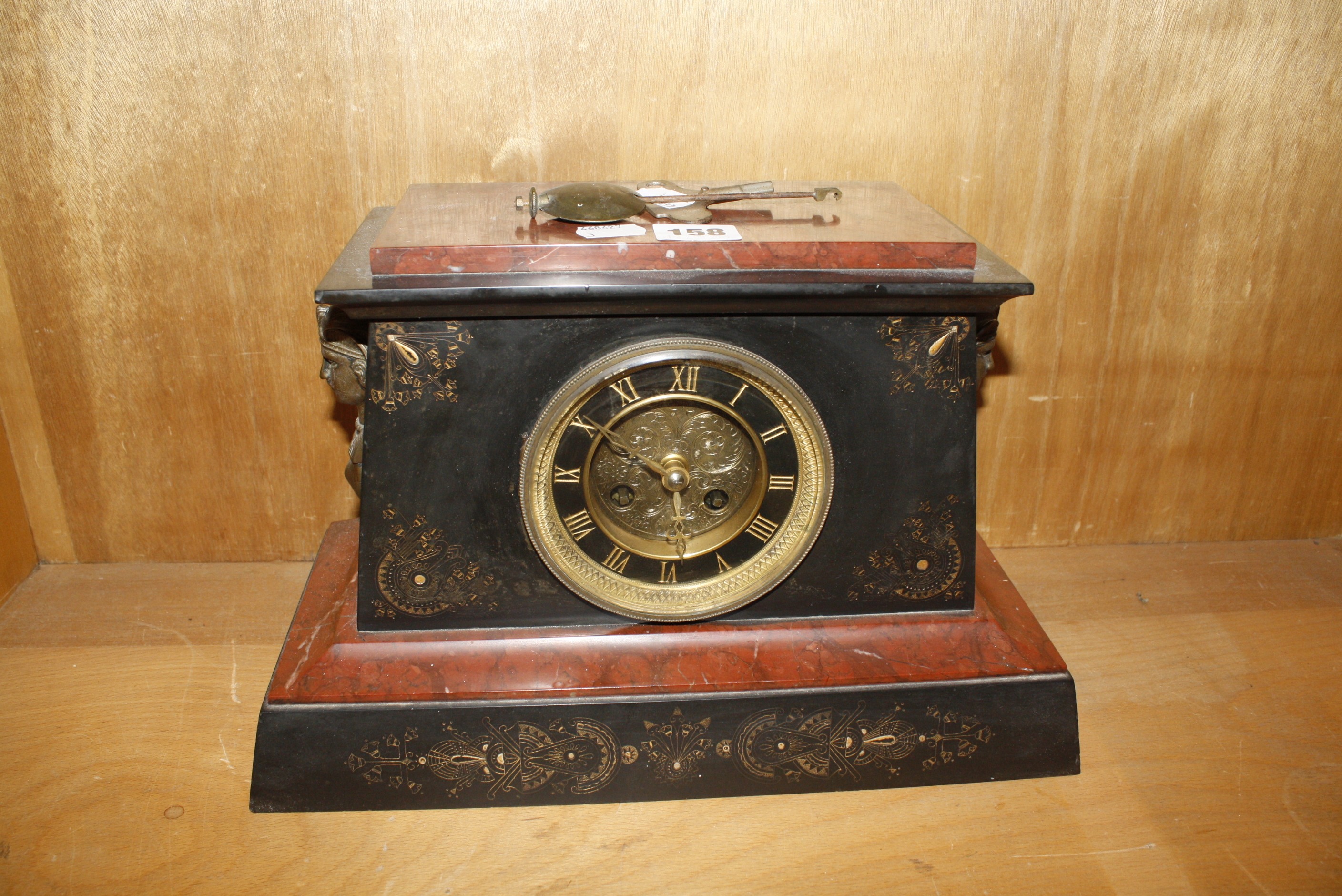 A French black slate and red marble mantel clock with Egyptian hieroglyphics and mask handles, 34.