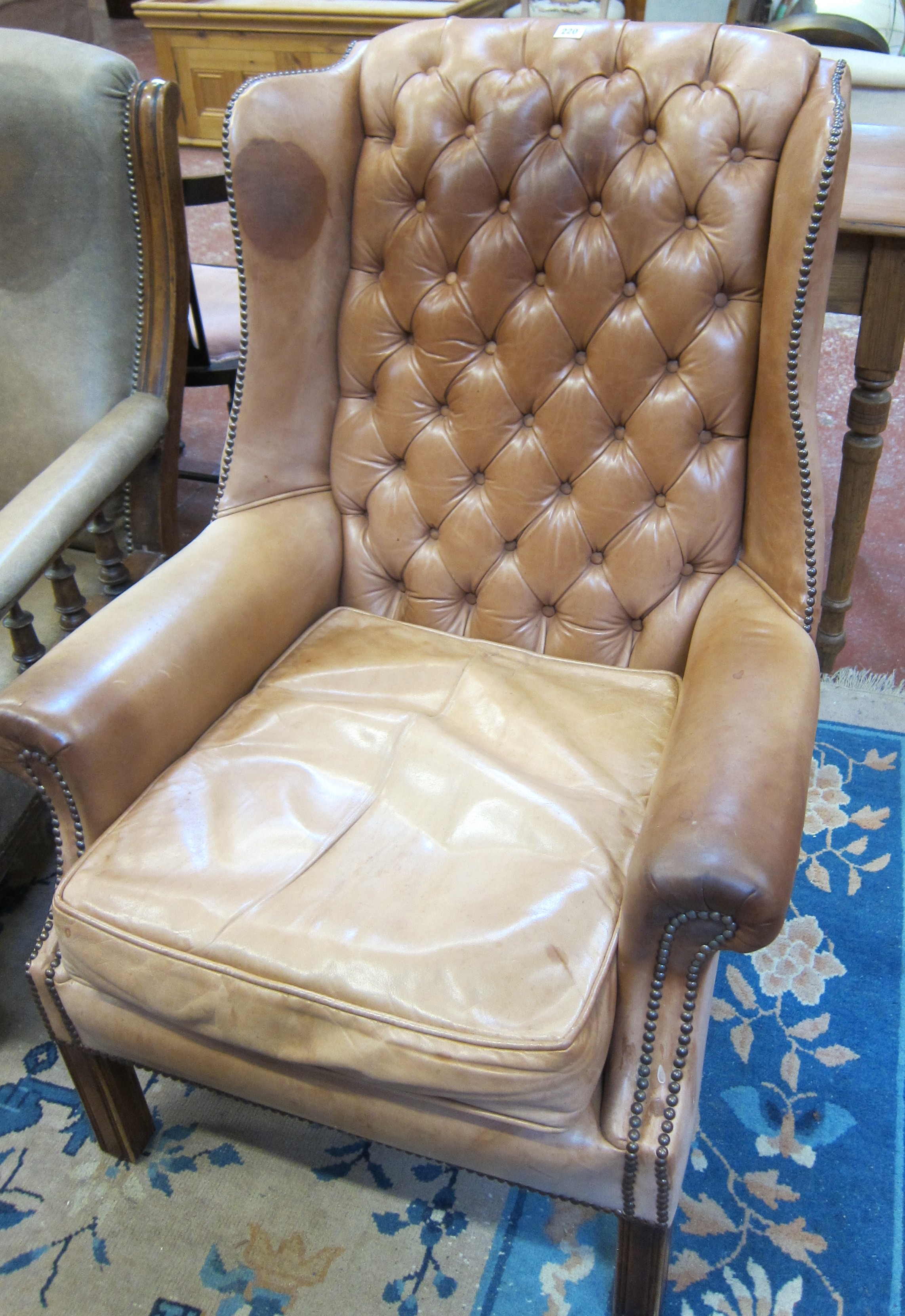 A Georgian style tan leather wing armchair.