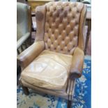 A Georgian style tan leather wing armchair.