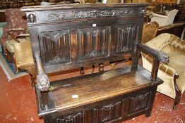 A 19th century oak settle with arms ending in lions head, linen fold back and hinged seat.131cm wide