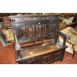 A 19th century oak settle with arms ending in lions head, linen fold back and hinged seat.131cm wide