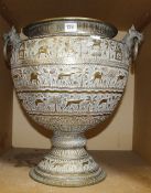 An Indian brass two handled urn, engraved with elephants and animals, with animal mask hoop handles,