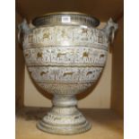 An Indian brass two handled urn, engraved with elephants and animals, with animal mask hoop handles,