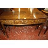 A bow front mahogany side table with three walnut faced drawers. 121cm wide.