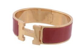 A Clic Clac hinged bangle by Hermes  , the two arms with red enamelled panels, to a central