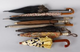 A collection of parasols and umbrellas, including: a 1920s silk example with a wooden handle, a