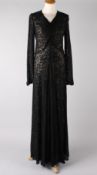 A 1930s full length black evening dress, with long sleeves, a simple V-neckline with ruching to