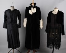 A black 1930s velvet evening coat with white fur trim; together with an Edwardian black dress, a