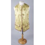 A late 19th/early 20th century yellow silk waistcoat edged with gold trimming and brass buttons,