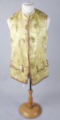 A late 19th/early 20th century yellow silk waistcoat edged with gold trimming and brass buttons,