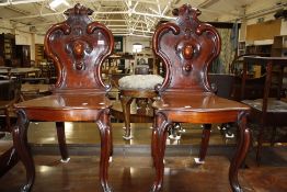 A pair of Victorian mahogany hall chairs with shield shaped backs and cabriole legs (2)