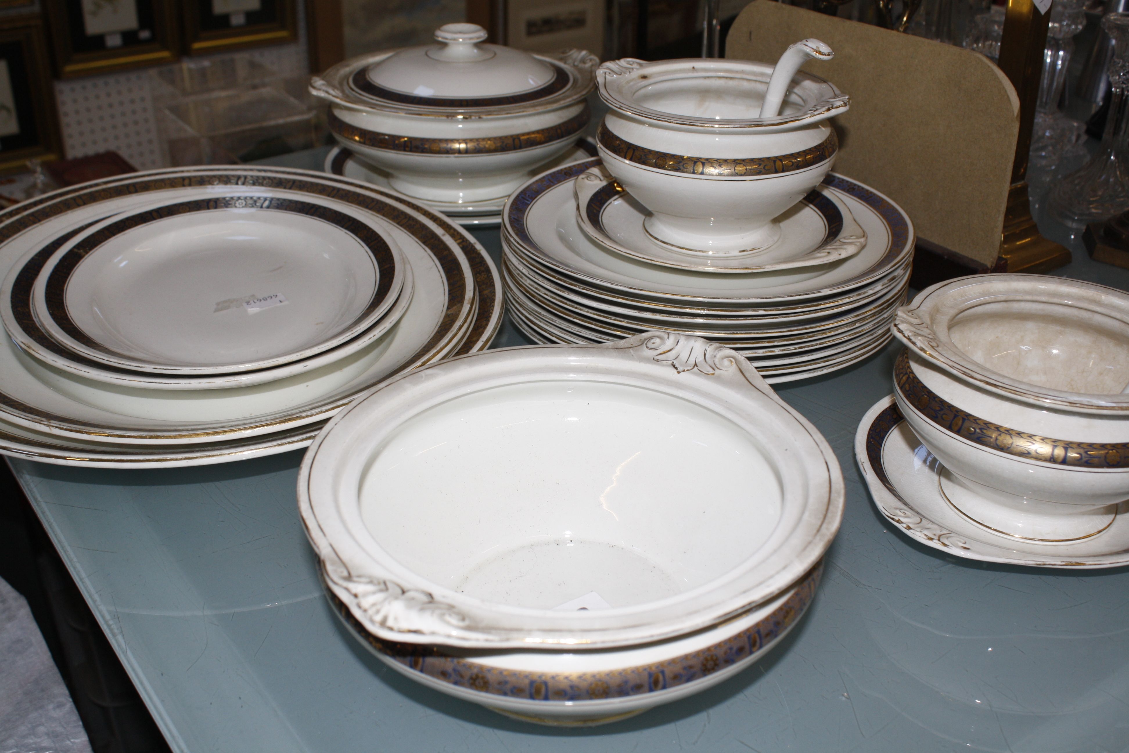 A part dinner service by Burleigh Ware, with a gold and blue border, to include tureens, serving