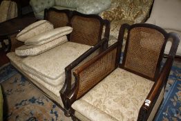 An early 20th Century cane bergere three piece suite with a coffee table