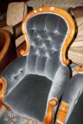 A Victorian mahogany framed button back armchair on turned legs with scrolled arms