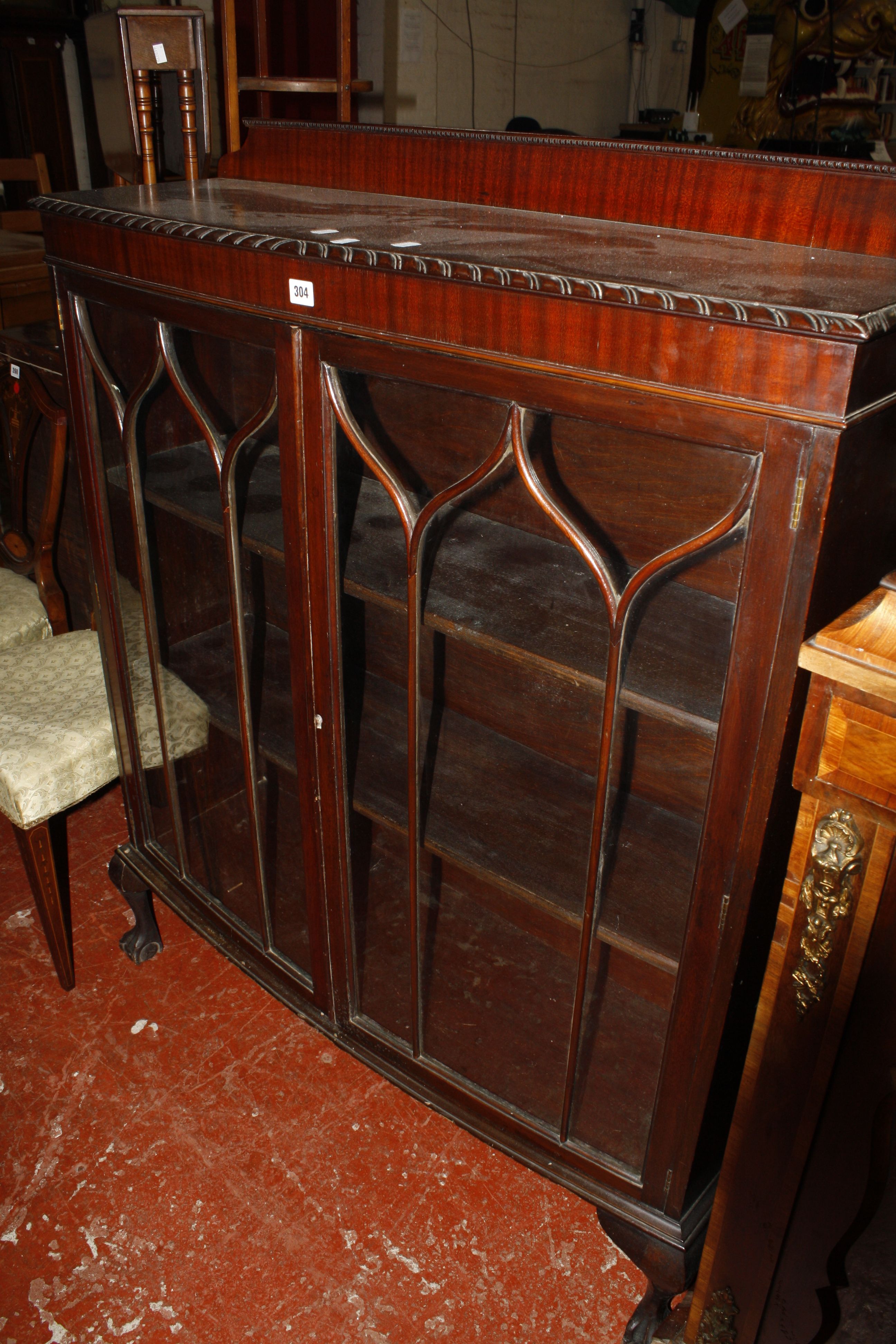 An early 20th century mahogany bow front display cabinet enclosed by a pair of tracery glazed doors,