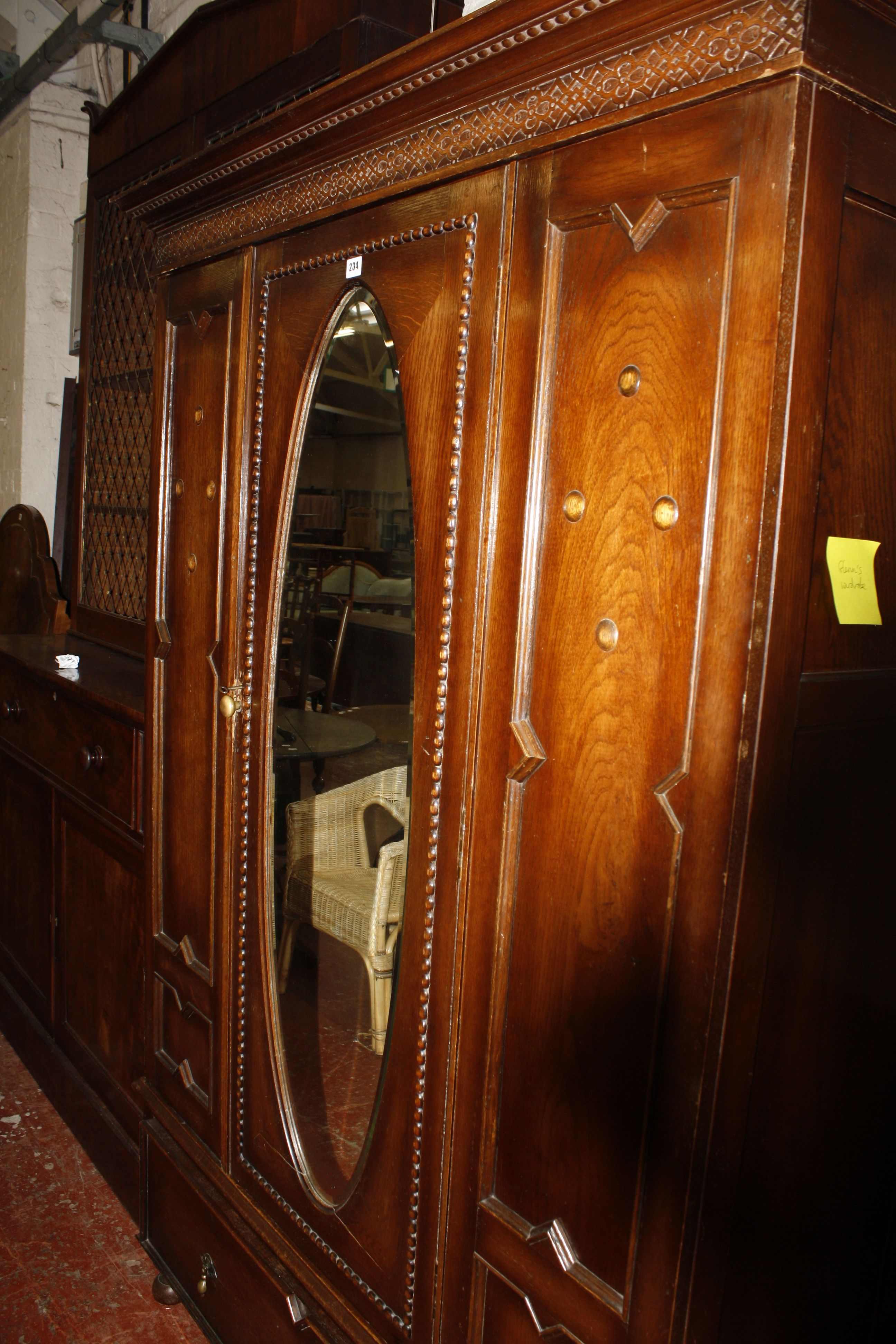 An oak wardrobe with mirror door and drawer below on bun feet