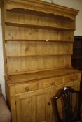 A pine dresser with shelves to the panelled back fitted with three drawers and two panel doors,