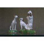 Three porcelain dogs on green and gilt bases, the tallest 7.5cm high approx.
