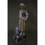 A Continental figure of a girl in 18th Century dress, standing by a watering can, round base, 22cm