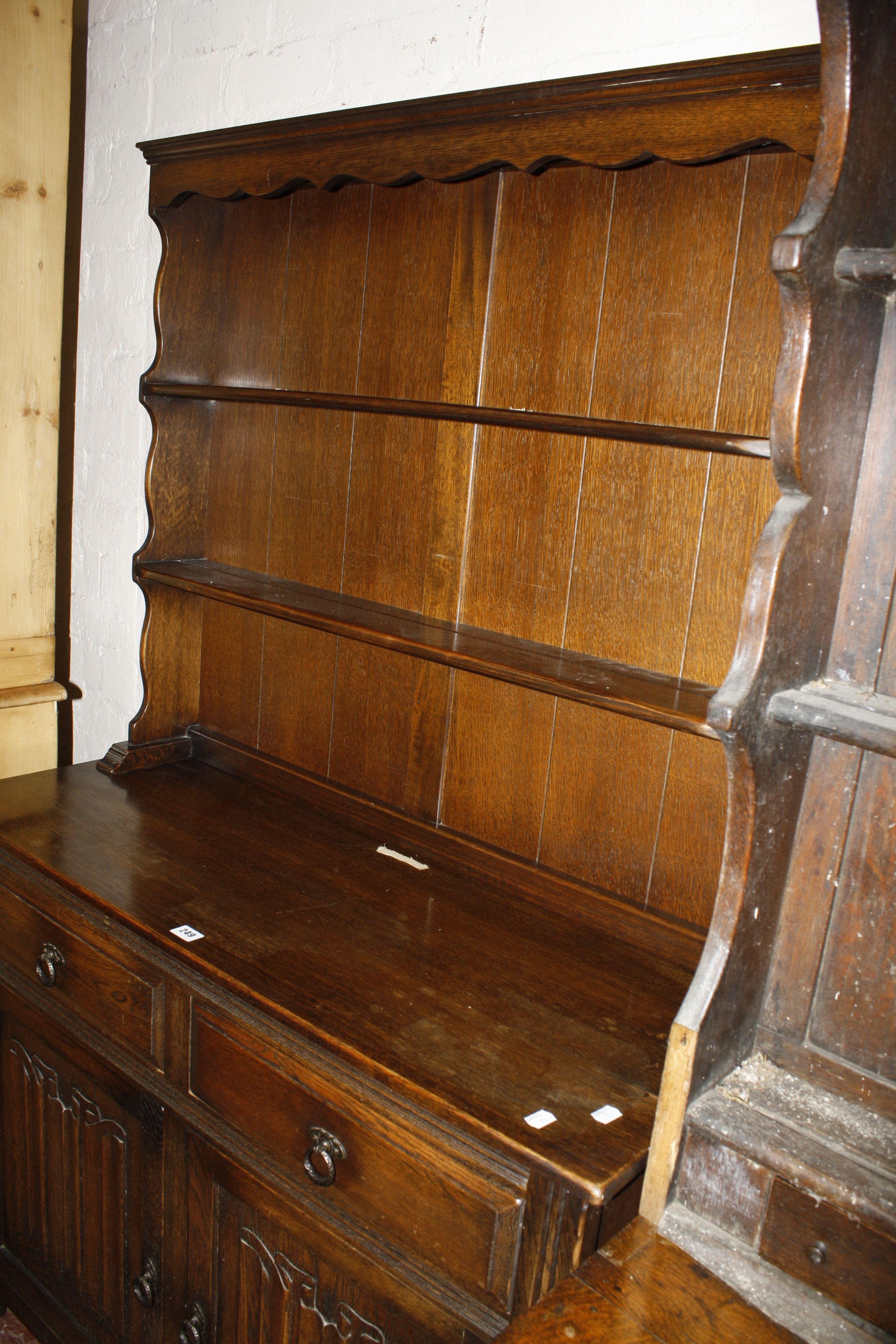 An oak linen fold dresser with a platerack and two drawers and cupboards 175cm high, 107cm wide