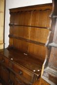 An oak linen fold dresser with a platerack and two drawers and cupboards 175cm high, 107cm wide