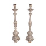 A pair of Spanish or Portuguese carved and silvered pine altar candlesticks  A pair of Spanish or