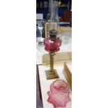 A Victorian oil lamp with cranberry glass shade and reservoir, on a brass reeded column base, 74cm