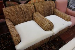 A pair of rattan armchairs with loose cushions