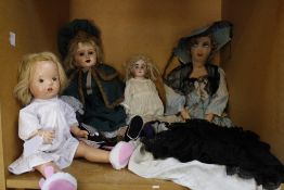 A small collection of early 20th Century English and Continental dolls, a doll's pram, a parasol, an