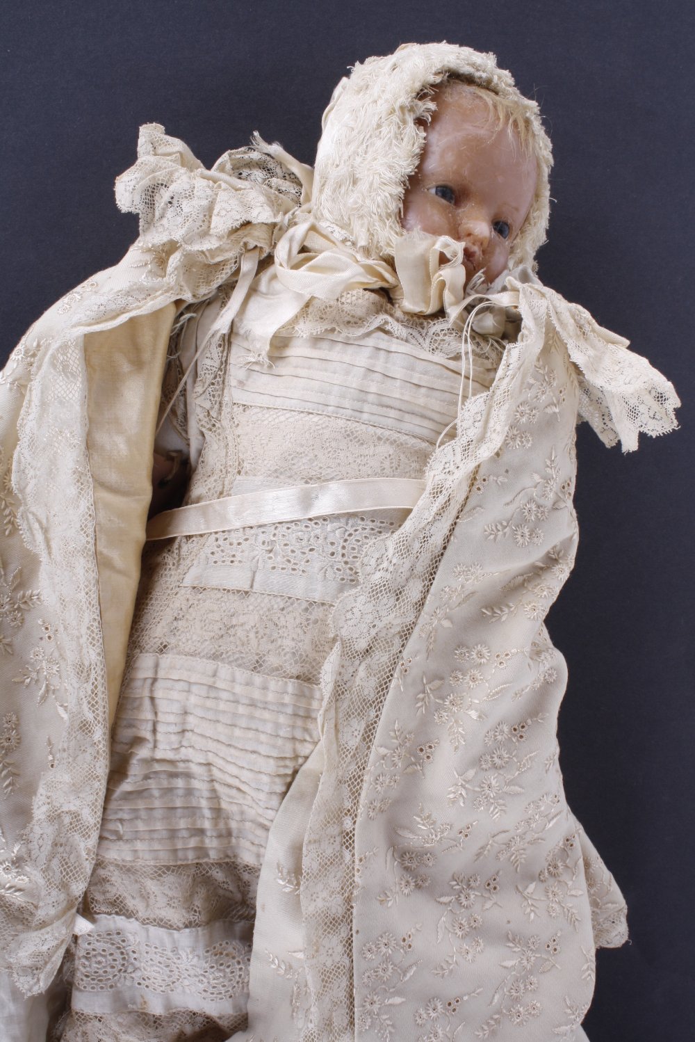 A 19th century baby doll. Wax head attached to a cloth body, blond human hair, stationary blue glass