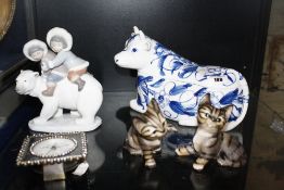 A Lladro figure of children riding a Polar bear, two model cats, a cow, a mantel clock and a