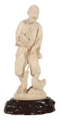 A Japanese Ivory Okimono of a Farmer, he stands holding a nest in one hand... A Japanese Ivory