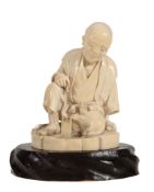 A Japanese Tokyo School Ivory Okimono depicting a waraji maker seated and... A Japanese Tokyo School