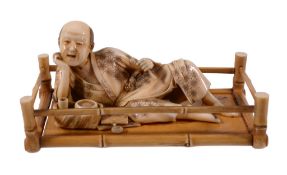 An Ivory Okimono of a Reclining Man , dressed in a diaper patterned loose... An Ivory Okimono of a