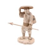 An Ivory Okimono of a Fisherman, he stands on an irregular base strewn with... An Ivory Okimono of a