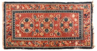 A Tibetan rug, circa 1900-1920, with a central panel of three stylised... A Tibetan rug, circa