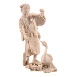An Ivory Okimono of a Farmer and Goose, the man stands on a rush mat holding... An Ivory Okimono