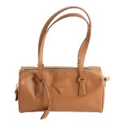 Prada, a tan textured leather barrel handbag,   with an applied Prada motif and optional padlock