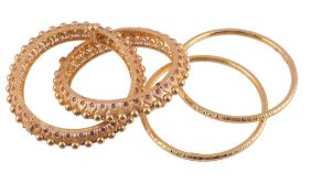 Four gold coloured bangles,   comprising two hinged bangles with red enamel accents, and a pair of