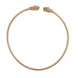 A gold torc necklace,   the hollow band set with a lion's head to each terminal, the eyes and head